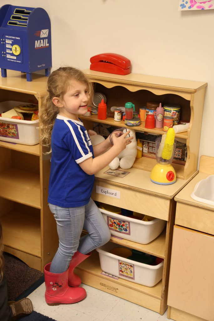 little girl playing with pretend play toys